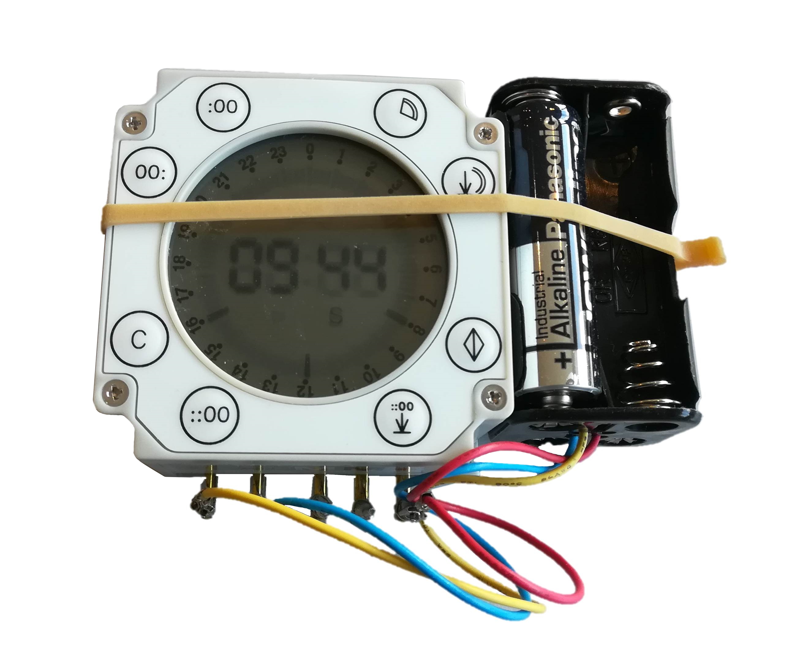 Weiße digitale Zeitschaltuhr mit LCD-Display (09:44) und Bedienelementen. Rechts schwarzer Batteriehalter mit Panasonic AA-Batterie. Unten farbige Anschlusskabel. Gelbes Gummiband hält die Baugruppe zusammen.