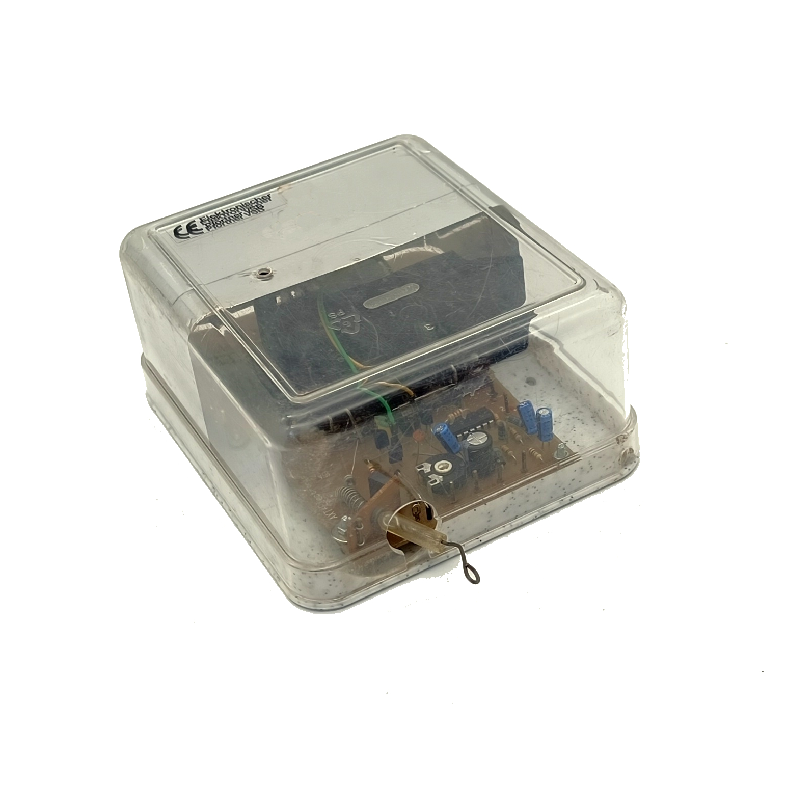Kleines transparentes Kunststoffgehäuse mit elektronischer Platine: blaue Kondensatoren, Widerstände und IC-Chip. Oben schwarzes Modul sichtbar. Vorn dünner Draht mit Öse. Auf dem Deckel: "Elektronischer Pförtner VSB".