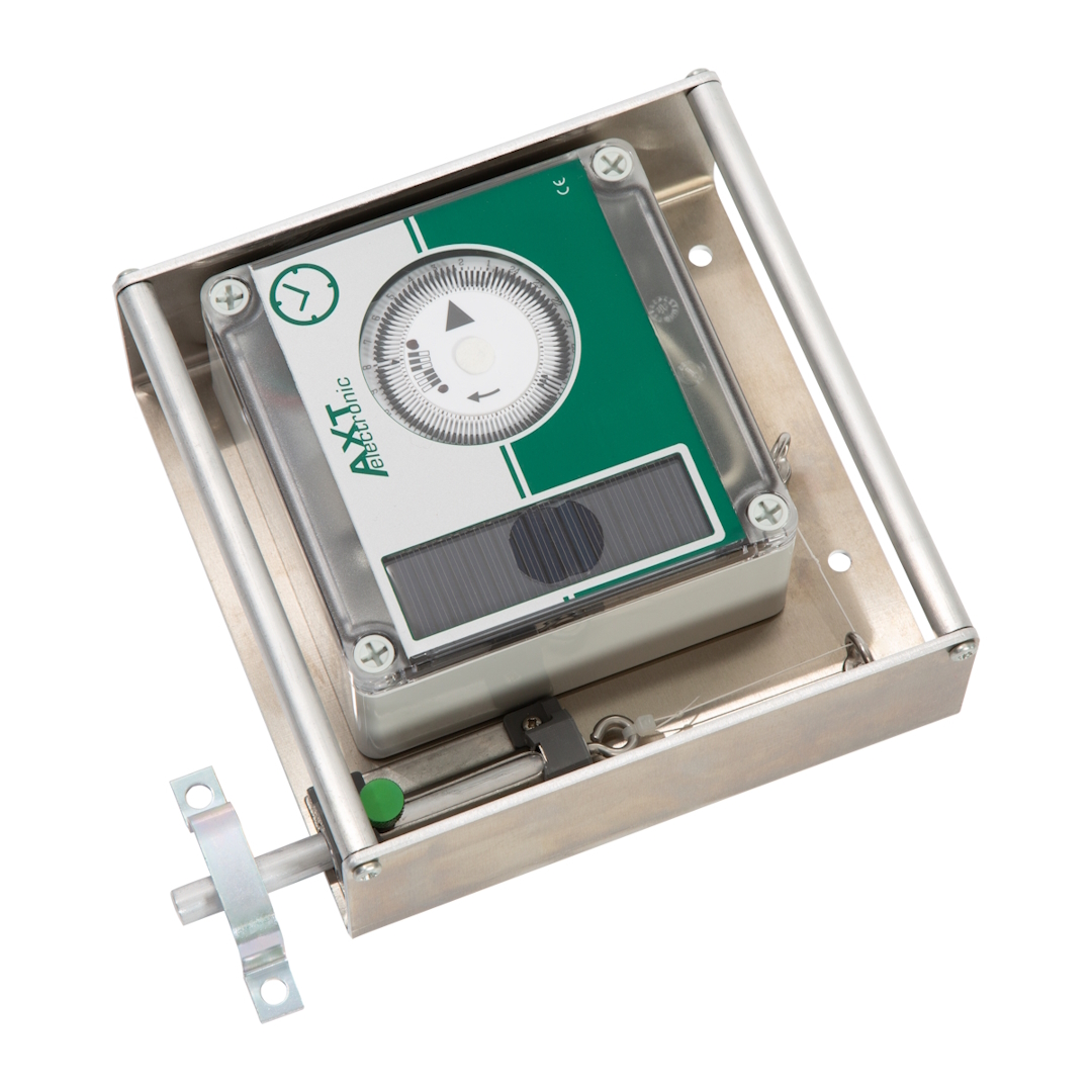 AXT electronic Steuergerät im silbernen Metallgehäuse, schräg von oben. Grüne Front mit weißem Zifferblatt zur Zeiteinstellung und darunter ein Solarpanel. Links Mechanismus mit grünem Knopf, Halterung und dünner Schnur.