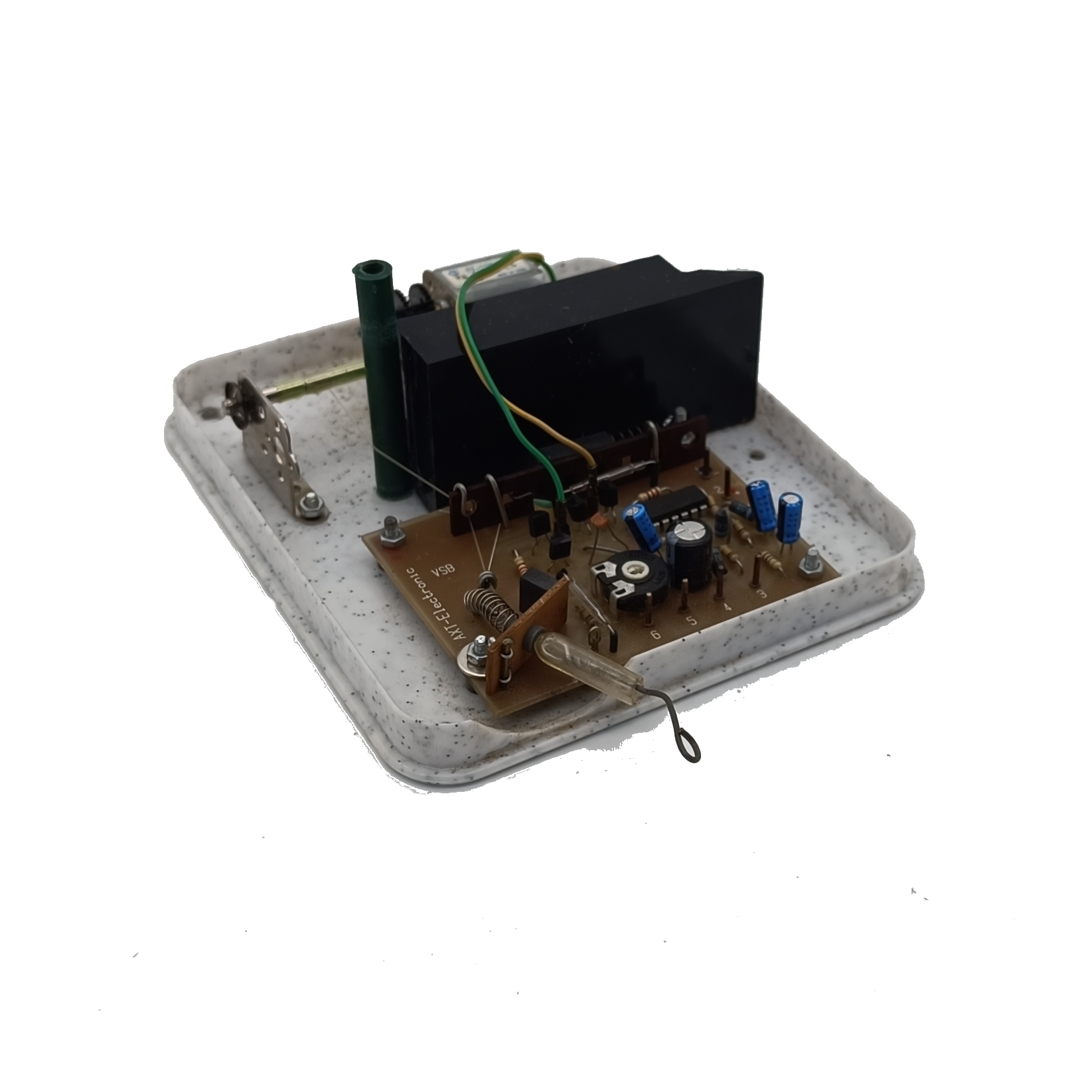 Offene Elektronikbox mit brauner Platine, bestückt mit schwarzem Transformator, blauen Kondensatoren, Widerständen, IC und farbigen Kabeln. Grüner Kunststoffschlauch und Metallklammer in gesprenkelter Schale. Gebogener Draht ragt heraus.