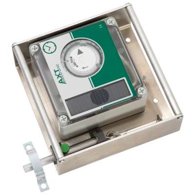Elektronischer Zeitgeber im Metallgehäuse, schräg von oben fotografiert, mit grün-weißer Frontplatte. Rundes Einstellrad mit Pfeilen und Uhr-Symbol, darunter dunkles Display. Links unten ein Riegelmechanismus mit grünem Knopf.
